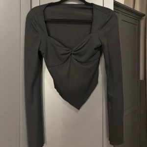 Svart långärmad topp med twistad front -  svart långärmad topp med twistad detalj framtill och spetsig nederkant.