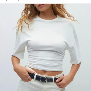 Vit croppad topp från Gina Tricot - Säljer en vit croppad topp från Gina Tricot i storlek S. Toppen har rund hals och snygga rynkade detaljer i sidorna som ger en cool och figurnära passform. Perfekt att styla med höga jeans eller kjol för en fräsch look. Helt oanvänd så därför säljer jag den för 200!