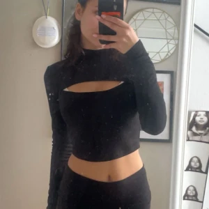 Svart croppad långärmad topp - (Välj 3 plagg för 70kr - gäller alla plagg som kostar mellan 20-40kr) Säljer en svart croppad långärmad topp med cool cut-out detalj över bröstet. Ribbat material som gör att materialet både känns och ser dyrare ut. 