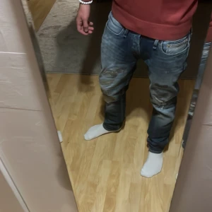 Mörkblå slitna jeans från Denham - Säljer ett par mörkblå jeans från Denham med snygga slitningar och distressed detaljer på framsidan. normal passform och klassisk knappgylf. Håller på att få en skön fade sitter bra för avslappnade tillfällen!! W29 L32 kan sänka pris vid snabb affär