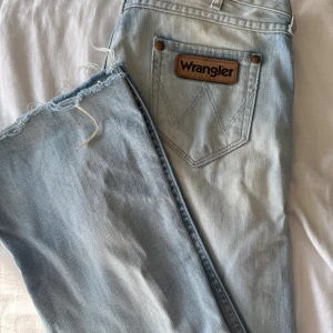 Wrangler ljusblå jeans W27 L32 - Ljusblå lågmidjade bootcut/straight jeans från Wrangler med klassisk brun logopatch på bakfickan. Super snygg blå färg. Jeansen är i bra skick, och nästan helt oandvända. 