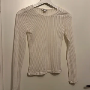 Vit ribbad långärmad topp Monki XXS - Säljer en vit, ribbad och lätt transparent långärmad topp från Monki i storlek XXS. Tight passform med rund halsringning och stretchigt material som sitter snyggt på kroppen. Perfekt att styla med jeans eller kjol för en clean look. Aldrig använd för var för liten och hann inte rösta i butiken 