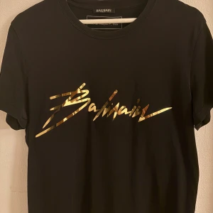 Svart Balmain t-shirt med guldtryck - En väldigt sällsynt och elegant Balmain T-shirt! Självklart äkta!
