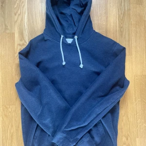 Mörkblå hoodie från Pier One - Mysig mörkblå hoodie från Pier One med huva och vita snören. Perfekt för chill dagar och enkel att matcha med jeans eller joggers. Långärmad och tillverkad i mjuk bomullsblandning för extra komfort.
