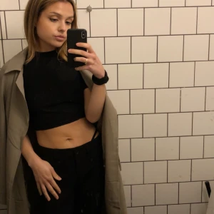 Beige trenchcoat med bälte - Säljer en  beige trenchcoat med bälte i midjan. Jackan har en avslappnad passform, klassisk krage och är tillverkad i ett lätt material som passar perfekt till vår och höst. Enkel att styla över vilken outfit som helst. Knappt använd. 