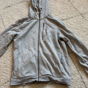 Grå hoodie från Sail Racing med dragkedja - Grå zip hoodie nästintill oanvända och i helt nyskick. I storlek 170 men skulle säga att den passar xs-s. Superfint skick verkligen. 