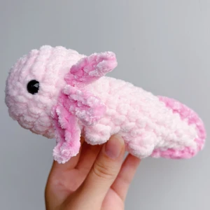 Virkad rosa axolotl - Rosa virkad axolotl – handgjord & unik🩷🧶 Superfin, mjuk och söt liten axolotl i rosa, perfekt som present eller för att ge lite extra charm till hyllan, soffan eller skrivbordet! 	•	Handgjord med kärlek 🩷 	•	Virkad i mjukt garn 	•	Ca 17-18cm lång 	•	Unik – bara ett exemplar!  ✨ Pris: 150 kr ✨  Passar både som prydnad och kramdjur 🧸OBS! Dessa innehåller säkerhetsögon som ej är rekommenderade för barn under 3 år!
