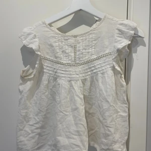 Vit blus med spetsdetaljer - Söt vit blus i luftig bomull med korta volangärmar och fina spetsdetaljer framtill. Skriv privat om ni vill ha mer info🩷