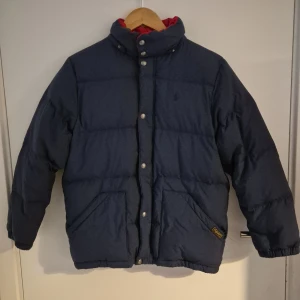 Ralph lauren vinterjacka  - Säljer en mörkblå Ralph Lauren vinterjacka. Den är i väldigt bra skick inga defekter men har tyvärr tappat bort luvan. Pris är diskuterbart. Storlek på bild 5
