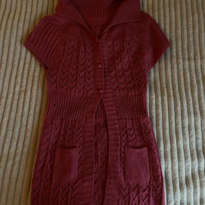 Rosa stickad kofta med krage - Supersöt rosa stickad kofta med snygg krage och korta ärmar. Koftan har dekorativa knappar framtill, två fickor och ett genomgående hålmönster som ger en unik look. Perfekt för dig som gillar stickade detaljer och vill ha något som sticker ut.