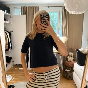 Mörkblå stickad topp - Säljer en mörkblå stickad topp med korta ärmar och croppad passform. Enkel och stilren design som passar perfekt till både jeans och kjol. Mjuk och skön att ha på sig, perfekt för vår och sommar.