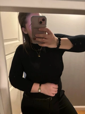 Svart trekvartsärmad tröja med knappar - Säljer en svart trekvarts ärmad tröja med snygga knappar längs ärmsluten. Tröjan har en klassisk och stilren look, perfekt att matcha med både jeans och kostymbyxor. Materialet känns mjukt och följsamt mot kroppen.