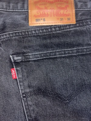 Levi's 501 svarta jeans W31 L32 - Svarta Levi's 501 jeans med klassisk röd etikett och läderpatch bak. Rak passform och femficksmodell i slitstarkt jeanstyg. Perfekta för dig som gillar en tidlös look med lite edge. Aldrig änvänd 