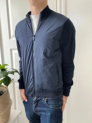 John Henric cardigan  - John Henric cardigan i mörkblå färg. Extremt clean och väldigt slim fit. Modellen är 180 cm 75 kg och är optimal passform. Storlek S. Inga defekter som helst heller 🙏🎉