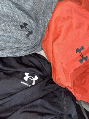 Under armour T-shirts  - Säljer dessa tre par under armour t-shirts 100kr st väldigt sköna att ha på sig den gråa och orange sitter oversize på kroppen och den svarta sitter lite mer tajtare.  knappast andvända