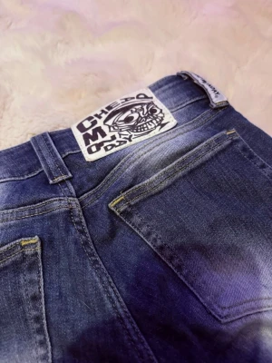Blå bootcut jeans med cool patch - Säljer ett par blå jeans från Cheap Monday med bootcut-modell och låg i midjan. Lite slitna längst ner❤️