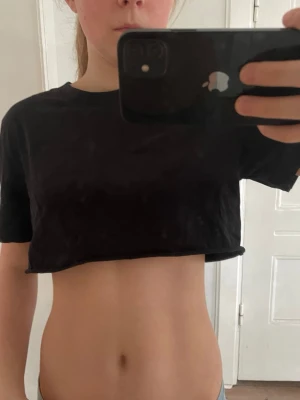 Svart croppad t-shirt - Enkel svart croppad t-shirt med rund hals och korta ärmar. T-shirten har en loose passform och är perfekt att styla med jeans eller kjol.