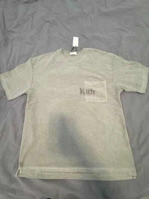 Grå t-shirt med ficka från Kith - Passar L också 