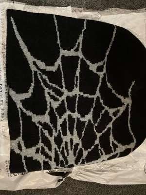 Y2K mössa helt ny - Säljer en svart stickad Y2K mössa med. Grått  spindelnätsmönster.