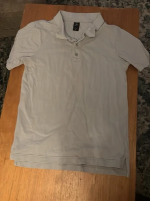 Vit pikétröja från Pilago - Klassisk vit pikétröja från Pilago i storlek S. Tröjan har korta ärmar, krage och knappar framtill. Perfekt till jeans eller shorts för en clean och enkel stil.