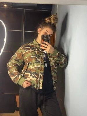 Camo bomberjacka från Junkyard  - Säljer en fet bomberjacka från Junkyard i camomönster med orange quiltat foder. Jackan har gröna muddar, dragkedja framtill och klassisk bomberstil. Perfekt för dig som vill sticka ut med streetstyle-vibe. Använd ett fåtal gånger, så den är i mycket bra skick.