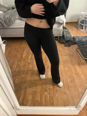 Svarta bootcut leggings - Säljer ett par svarta leggings med bootcut-modell. De har en låg midja och är tillverkade i ett stretchigt material som sitter skönt på kroppen. Perfekta för dig som gillar en enkel och clean look med lite utsvängda ben. Har fått en skada på vänster knä men inget som syns om man inte kollar för noga