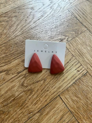 Två par orangea örhängen  - Säljer två par orangea örhängen, det ena paret är en droppform och det andra paret är kvadratiska ”hoops”. Passar perfekt för dig som gillar statementörhängen eller bara vill spicea upp din outfit! 