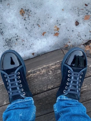 Svarta sneakers från Lanvin i mocka - Säljer ett par svarta sneakers från Lanvin med snygg kontrast mellan mocka och lackdetaljer på tån. Skorna har rund tå, snörning och platt sula. Perfekta för dig som vill ha en clean men ändå lyxig look. Passar till jeans eller mer dressade outfits. Dustbag medföljer