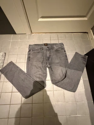 Grå Lee Luke jeans W31 L32 - Säljer ett par grå jeans från Lee, modell Luke. Klassisk femficksdesign, raka ben och normal passform. Jeansen är tillverkade i mjuk bomull med en snygg tvättad look. Perfekta till en avslappnad stil.