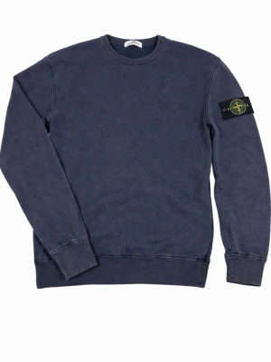 Mörkblå sweatshirt från Stone Island - Säljer en mörkblå sweatshirt från Stone Island i 100% bomull. Klassisk rund halsringning och ribbade muddar vid ärmslut och nederkant. Perfekt basic tröja med ikonisk patch på ärmen för en clean och stilren look.  Storlek 14 (170). Äkta med QR/Certilogo på taggen (se bilder). Bra skick, inga hål eller fläckar.  Kan skickas direkt 📦✨