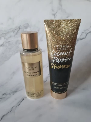 Victoria's Secret Coconut Passion Shimmer duo - Säljer ett set med Victoria's Secret Coconut Passion Shimmer, innehållande en shimmer body mist (250 ml) och en shimmer lotion (236 ml). Båda har en tropisk kokosdoft och guldigt skimmer. Flaskan och tuben har snyggt guldigt och svart design med metallic-detaljer. Bodylotion helt oanvänd bodymisten provsprutad några gånger se bilderna