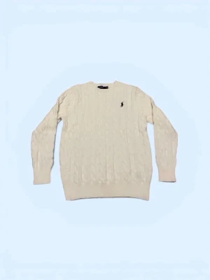 Vit kabelstickad tröja Polo Ralph Lauren - Kabelstickad vit tröja från Polo Ralph Lauren med klassisk svart broderad logga på bröstet. Tröjan har rund halsringning, ribbade muddar och är långärmad. Perfekt för dig som gillar stilrena och tidlösa plagg.