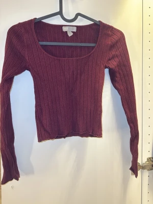 Vinröd ribbad tröja från ASOS - Säljer en vinröd ribbad tröja från ASOS. Toppen är croppad och har en varm, mjuk, stretchig känsla som gör den skön att bära. 