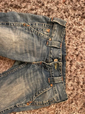 True Religion lågmidjade jeans, storlek 26 - Säljer ett par blå lågmidjade jeans från True Religion. Bootcut och snygga detaljer på bakfickan. Tillverkade i USA i slitstarkt denimtyg. Säljer de pga att de är för små
