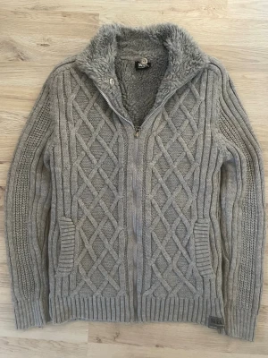 Fodrad stickad cardigan - Otroligt fet grå fodrad stickad cardigan med mönster. Passar perfekt till kallare väder. Priset kan såklart diskuteras!