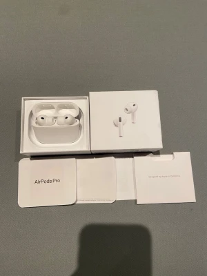 AirPods Pro - Apple AirPods Pro i mycket fint skick, komplett med originalförpackning, manualer och extra öronkuddar. Trådlösa hörlurar med aktiv brusreducering och laddningsetui. Perfekt för musik, samtal och träning. Inga synliga defekter eller slitage.