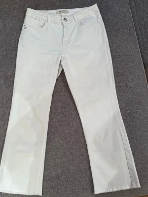 Vita jeansbyxor från Mos Mosh - Snygga vita jeansbyxor från Mos Mosh med raka ben och rå kant nertill. Klassisk femficksmodell med silverfärgade detaljer och knapp. Tillverkade i mjuk bomullsmix som ger en skön känsla. Perfekta för dig som gillar stilrena och fräscha byxor.
