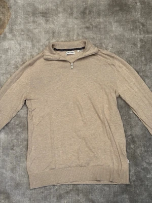 Beige half zip tröja Jack & Jones - Säljer en beige långärmad tröja från Jack & Jones i storlek M. Tröjan har en stilren half zip-dragkedja vid kragen och är gjord i mjuk bomull. Perfekt för lager på lager och enkel att matcha med det mesta.