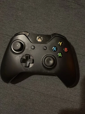 Xbox One Wireless Controller - Trådlös Xbox One-kontroll i svart. Kontrollen har tydliga knappar och spakar, samt anslutning för headset. Något bruksslitage syns men fungerar utmärkt för spel på Xbox One eller PC. Perfekt för extra spelare eller som ersättningskontroll.