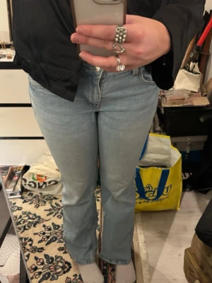 Ljusblå bootcut jeans från Divided H&M - Säljer ett par ljusblå jeans från Divided H&M i storlek 40, de är med åt storlek 38. De har klassisk femficksdesign, knappstängning bak på fickorna och bootcut-ben. Perfekta för dig som gillar en retro vibe och vill ha ett par jeans som sitter snyggt över höfterna.