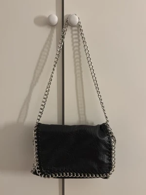 Tiamo Pricilla - Säljer den populära Tiamo Pricilla handväskan i storlek M. Köpt från Scorett. Väskan har en dragkedja på baksidan. I jättebra skick. Gåva vid köp!🎁