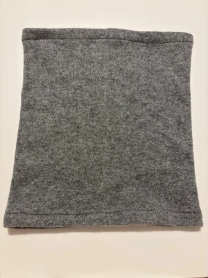 Grå kashmir buff - En enkel och mjuk grå buff i 100% kashmir. Perfekt att dra över huvudet för extra värme under kyliga dagar. Tidlös design utan mönster eller detaljer, passar till det mesta.