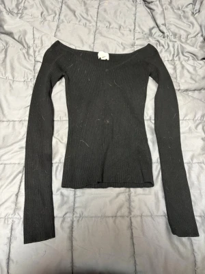 Svart ribbad offshoulder topp H&M - Säljer en svart ribbad offshoulder topp från H&M i storlek XS. Toppen har lång ärm och är figurnära med stretchigt material.
