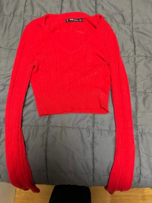 Röd croppad stickad tröja FB Sister - Säljer en röd croppad stickad tröja från FB Sister i storlek XS. Tröjan har v-ringning, ribbade muddar och lång ärm. 