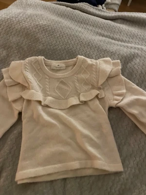 Beige stickad tröja med volang H&M - Supersöt beige stickad tröja från H&M med volangdetaljer över axlarna och kabelstickat mönster framtill. Tröjan har används bara några enstaka gånger den blir större när man har på sig den. Perfekt för lite finare middagar men ändå kausal. Pris kan förändras på bra förslag