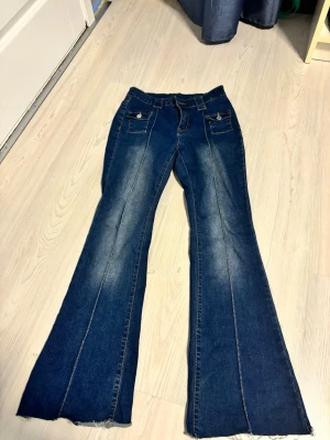 Blå bootcut jeans med fickdetaljer Shein - Jeansen har markerade sömmar och slitningar längs benen för en cool look. 