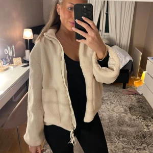 Teddyjacka/kofta med dragkedja - Mysig beige teddyjacka/kofta med krage och dragkedja framtill. Aldrig använd. Känns som en XS/S. Jackan har två stora fickor och en relaxed, lite oversized passform. 