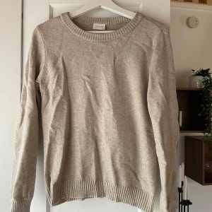 Beige stickad tröja från vila - Säljer en stilren beige stickad tröja från vila. Tröjan har en rund halsringning och långa ärmar med ribbade muddar. Perfekt för kyliga dagar och enkel att matcha med olika outfits.