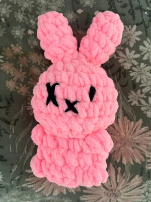 Handgjord rosa plysch-kanin - Supergosig och unik liten kanin i fluffigt, mjukt garn. Den är handgjord och har en charmigt quirky stil med korsade ögon i svart broderi. Perfekt som dekoration, present eller som ett gulligt samlarobjekt. För dig som älskar cute, handmade och lite quirky plushies! 💗