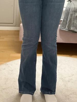 Blå bootcut jeans med broderade fickor - Snygga blå bootcut jeans från Nelly med låg midja och klassisk femficksdesign. Jeansen har broderade detaljer på bakfickorna och är tillverkade i mjukt denim med lätt stretch. Perfekt passform och cool tvättad look. Säljer dessa för att de är lite för korta för mig som är 173 cm, och dessutom har de blivit för små för mig. 